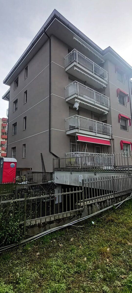 Recinzione di cantiere e box di servizio addossati al fianco della palazzina.